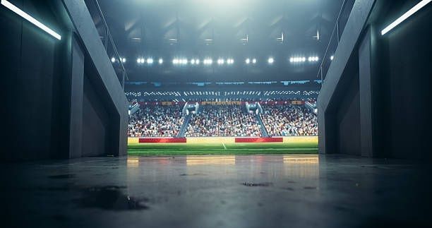 Couloir sombre ouvrant sur un stade éclairé et rempli de spectateurs